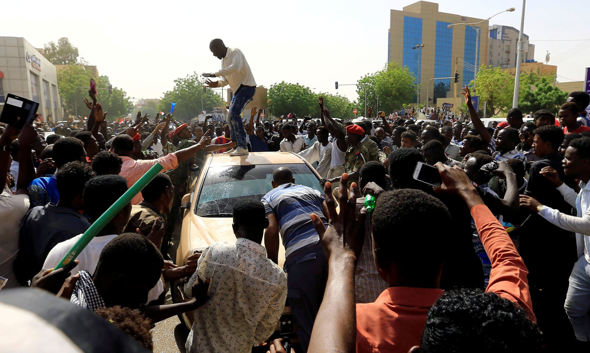 Sudanese demonstrators block the car of an army officer in Khartoum